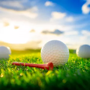 close-up-the-golf-ball-and-red-tee-pegs-on-the-green-background-with-sunset