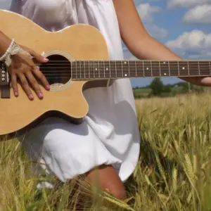 Country girl with guitar at wheat field