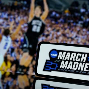 March madness logo on screen an basketball gameplay on TV screen in the background.
