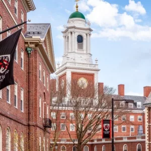 View of the architecture of the famous Harvard University in Cambridge^ Massachusetts^ USA showcasing it brick buildings with some students and locals passing by . Cambridge^ MA^ USA - March 15^ 2024