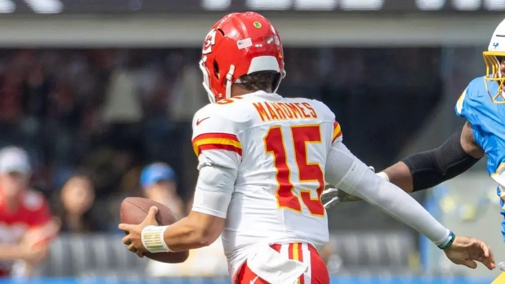 KC Chiefs quarterback Patrick Mahomes #15 runs to escape a tackle by LA Chargers outside linebacker Bud Dupree #48 during an NFL football game at SoFi Stadium Sept. 17, 2024, in Inglewood, Calif.