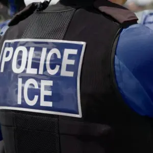 ICE police agent - Officer of Immigration and Customs Enforcement. Close-up of POLICE ICE marking on the back of a stab proof vest uniform worn by a trio of police officers at the scene of an immigrant incident. The ICE federal law enforcement agency is under the supervision of the United States Department of Homeland Security.