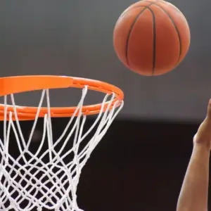 Orange basketball ball flying into the basketball hoop