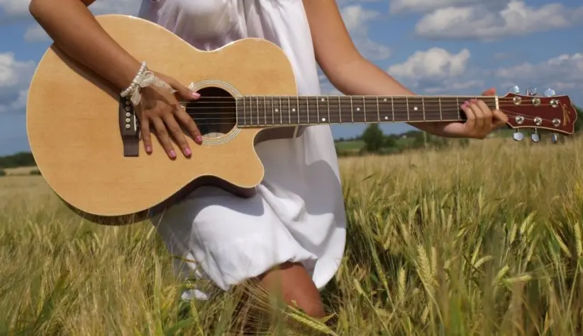 Country girl with guitar at wheat field