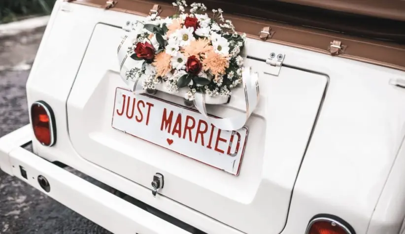 'JUST MARRIED" sign with flower decoration on white wedding car