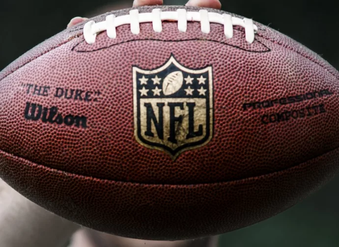 NFL professional athlete holds a ball for American football.