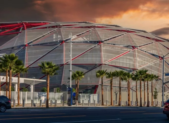 The Intuit Dome with cars driving on the street^ lush green palm trees and powerful clouds at sunset in Inglewood California USA. Inglewood^ California USA - 10 22 2024