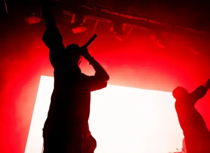 Silhouettes of two singers on the stage. Music band on the stage^ red lightning. Rappers pulling out their hands on the stage.