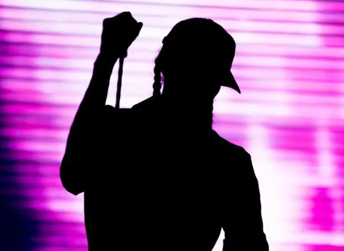 Silhouette of an artist singing live on the stage in the front of a colorful background