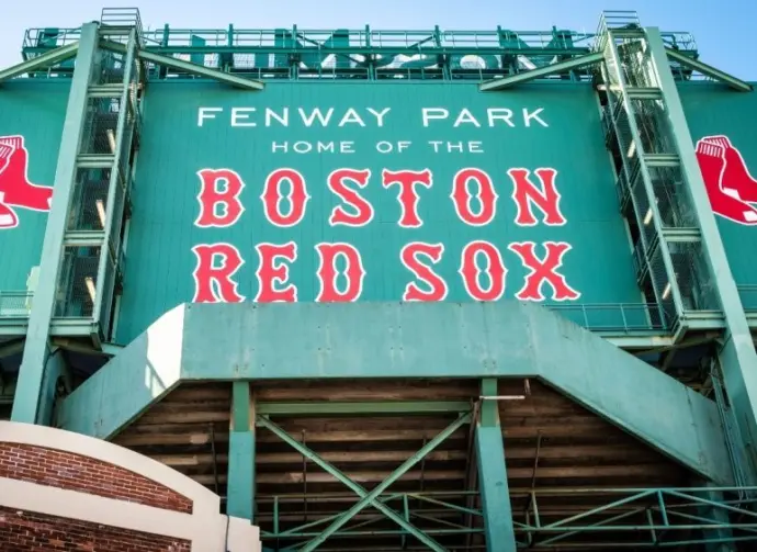 View of the historic architecture of the Fenway Park Stadium showcasing its signs^ brick walls^ statues^ and the famous green color and red letters of the red sox. Boston^ MA^ USA - March 10^ 2023
