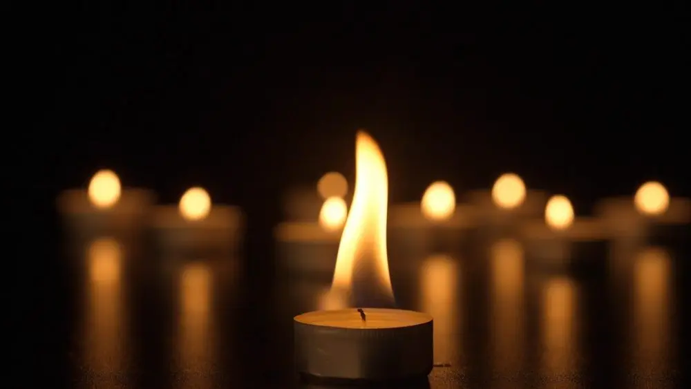 Burning candles. The candles burn against a black background and the flames move when the wind blows. The concept of a memorial day. Background for advertising and design projects.