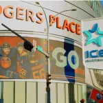 Edmonton Oilers hockey team fans waving flags outside Rogers Place stadium^ with Oilers hockey players pictured on the LED billboard. Edmonton^ Alberta^ Canada
