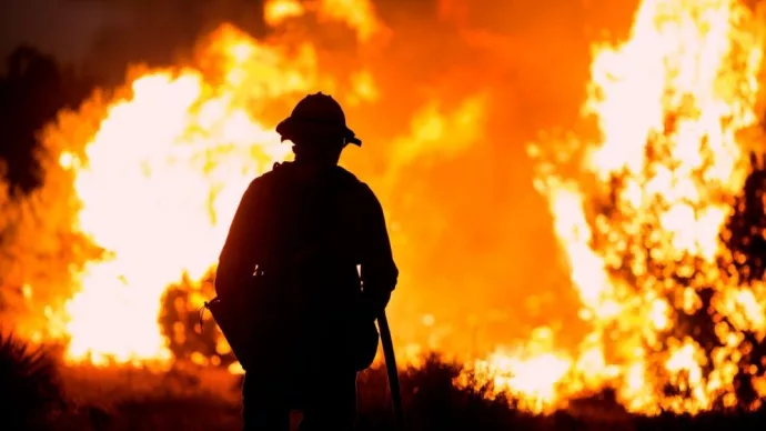 A firefighter watches as the Bobcat Fire burns in Juniper Hills^ California^ Saturday^ Sept. 19^ 2020.