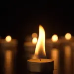 Burning candles. The candles burn against a black background and the flames move when the wind blows. The concept of a memorial day. Background for advertising and design projects.