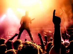 silhouette of guitar player in action on stage in front of concert crowd