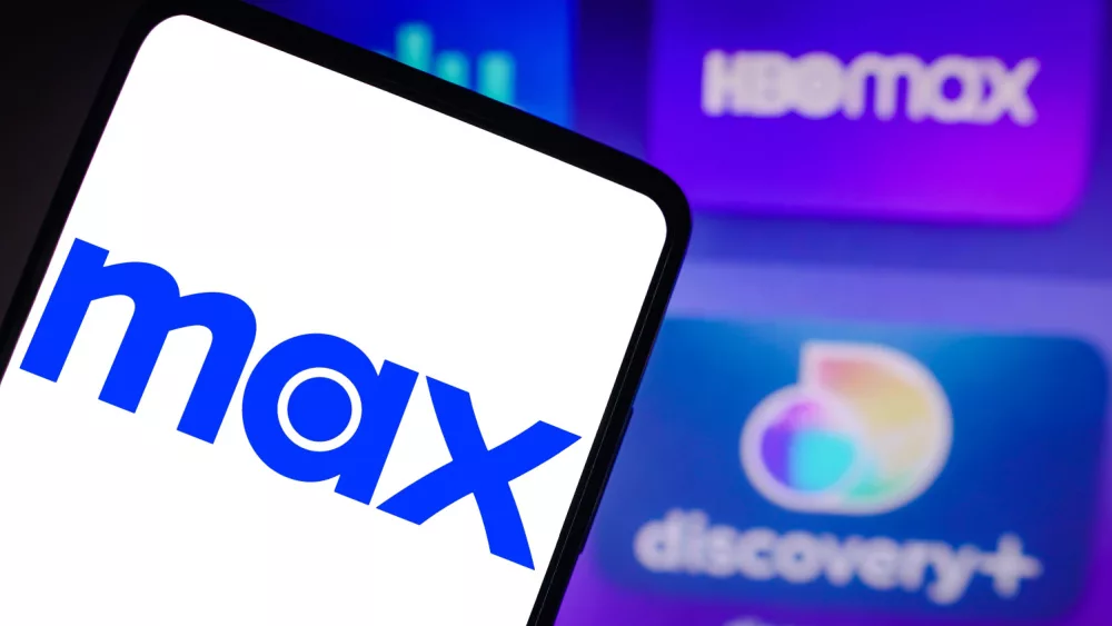 Photo illustration of the Max logo is seen displayed on a smartphone and the HBO Max and Discovery logo on the background