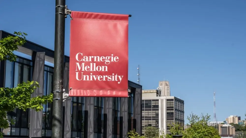 Carnegie Mellon University campus entrance sign with buildings in the background. Pittsburgh^ Pennsylvania^ USA- May 13^ 2021: Carnegie Mellon University campus entrance sign with buildings in the background. CMU is a private research university