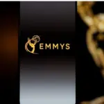 Emmys logo displayed on a smartphone screen with a blurred gold award statuette in the background^ television industry awards and digital streaming concept. Kaunas^ Lithuania - 2026 March 24