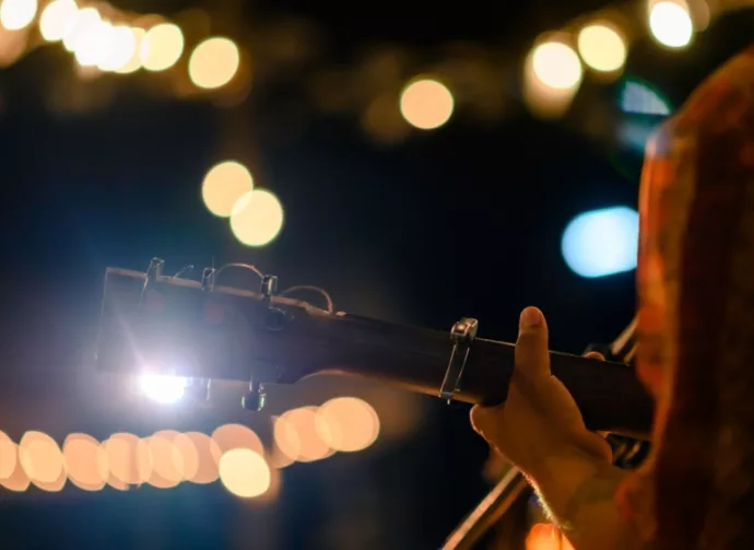 Man play acoustic guitar at outdoor concert with a microphone stand in the front^ musical concept.