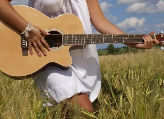 Country girl with guitar at wheat field