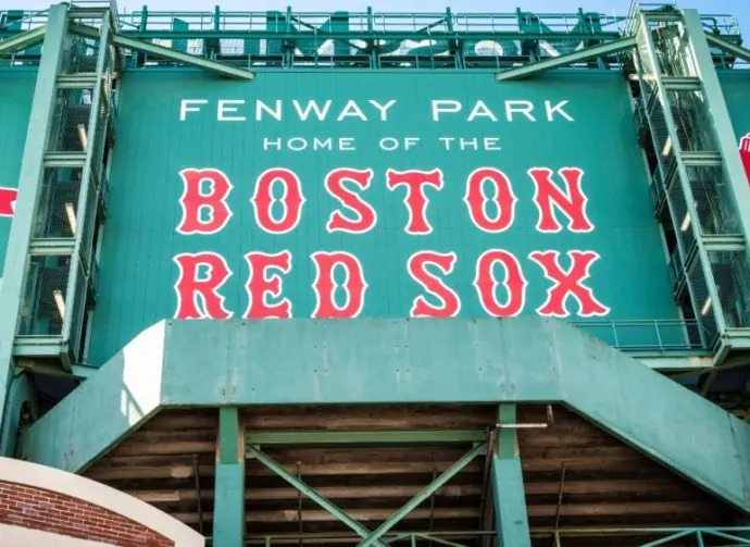 View of the historic architecture of the Fenway Park Stadium showcasing its signs^ brick walls^ statues^ and the famous green color and red letters of the red sox. Boston^ MA^ USA - March 10^ 2023