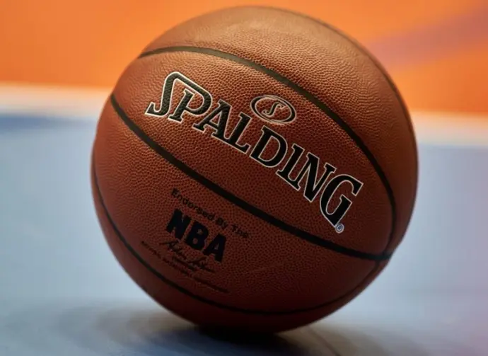 Gdansk^ Poland - 08 02 2024: Close-up of a Spalding NBA basketball resting on a blue and orange court^ focusing on the texture of the ball and the surrounding vibrant colors of the court.