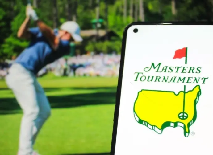 Masters Tournament logo displayed on a mobile phone with a photo of a player taking a swing on its website in the background^ the world's premier golf championship. Indonesia - May 15^ 2025