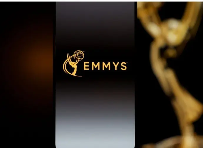 Emmys logo displayed on a smartphone screen with a blurred gold award statuette in the background^ television industry awards and digital streaming concept. Kaunas^ Lithuania - 2026 March 24