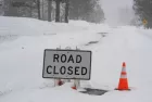 "Road Closed" sign during atmospheric river winter storm event in the Sierra Nevada mountains.