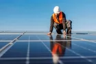 A worker installing solar panels on the roof