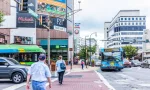 Downtown area of city in Maryland with cars on street^ bus^ and shopping mall stores^ shops and people.