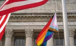 Waving Pride LGBT flag next to the flag of USA