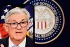 Federal Reserve (Fed) Chair Jerome Powell is visible on smartphone screen. In the background^ an inflation rate chart is displayed.