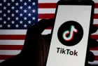 Photo illustration of TikTok logo displayed on a smartphone with American Flag in the background.