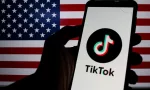 Photo illustration of TikTok logo displayed on a smartphone with American Flag in the background.