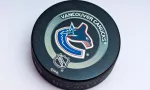 Official Vancouver Canucks game puck on the ice ^product shot