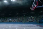 empty basketball court; shot of hoop and crowd in background
