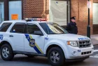 A uniformed Philadelphia Police officer stands beside a police vehicle. PHILADELPHIA^ PA - JANUARY 1^ 2015