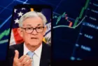 On the smartphone screen^ Federal Reserve (Fed) Chair Jerome Powell is visible. In the background^ an inflation rate chart is displayed. 19.04.2025. New York^ U.S