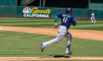 Seattle Mariners infielder Carlos Santana runs to first base against the Oakland Athletics at the Oakland Coliseum. Oakland^ California - August 21^ 2022