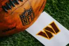 Washington Commanders NFL team Logo and American football ball on Green Grass.