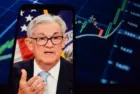 Federal Reserve (Fed) Chair Jerome Powell is visible. In the background^ an inflation rate chart is displayed.