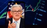 Federal Reserve (Fed) Chair Jerome Powell is visible. In the background^ an inflation rate chart is displayed.