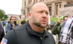 Alex Jones^ flanked by bodyguards^ leaves a rally protesting Covid-19 stay at home orders at the Capitol that was heavily promoted by his Infowars website. Austin^ Tx/USA - Apr. 18^ 2020