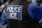ICE police agent - Officer of Immigration and Customs Enforcement. Close-up of POLICE ICE marking on the back of a stab proof vest uniform worn by a trio of police officers at the scene of an incident