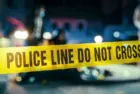 Yellow Tape Showing Text "Police Line Do Not Cross" Restricting a Crime Scene Area At Night. Close Up Aesthetic Shot with Bokeh Effect and Flickering Lights. Criminal on the Loose Strikes Again