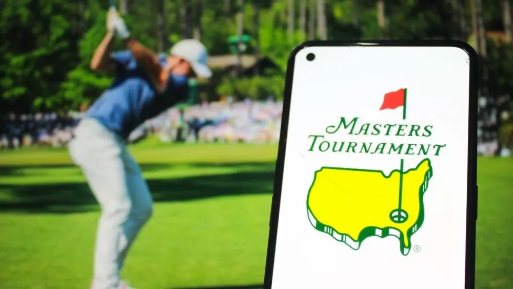 Masters Tournament logo displayed on a mobile phone with a photo of a player taking a swing on its website in the background^ the world's premier golf championship. Indonesia - May 15^ 2025