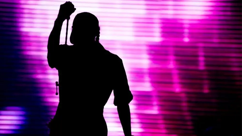 shutterstock_683825146-1852858 Silhouette of an artist singing live on the stage in the front of a colorful background