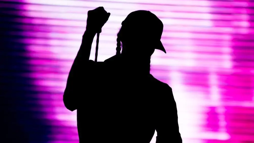 shutterstock_683825140119193 Silhouette of an artist singing live on the stage in the front of a colorful background