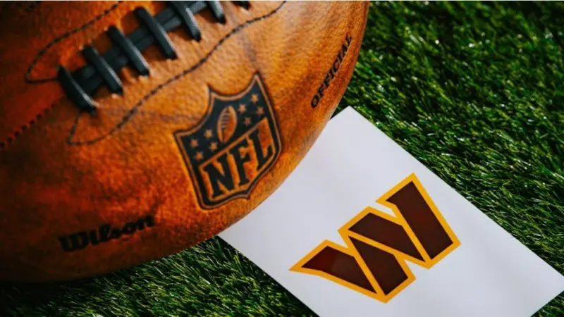 Washington Commanders NFL team Logo and American football ball on Green Grass.